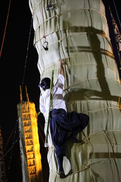 松明にはしごを使わずよじ登り、点火します