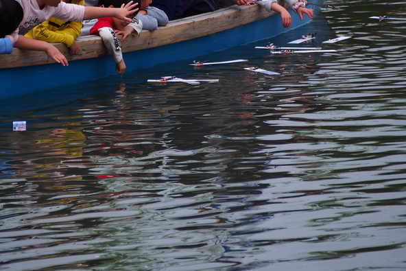 どんこ舟に乗り込んだ子供たちが短冊を川へ流します
