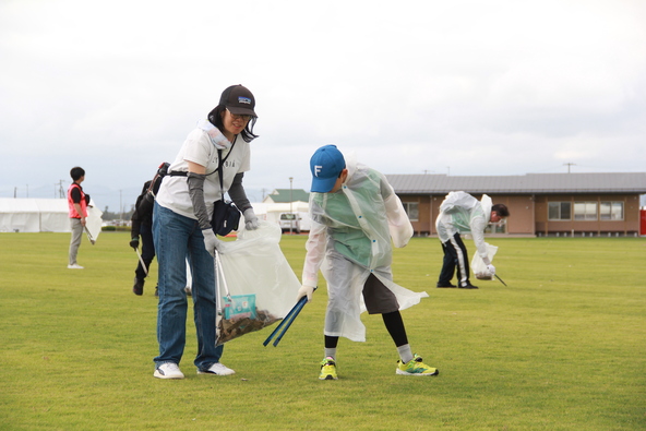 参加者が協力して芝生の会場を清掃します