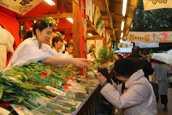金色の烏帽子（えぼし）をかぶった福娘たちが福笹（ふくざさ）に吉兆を結びつけます