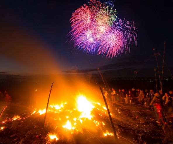 燃え盛るどんど焼きの炎と花火が冬の夜空を彩ります